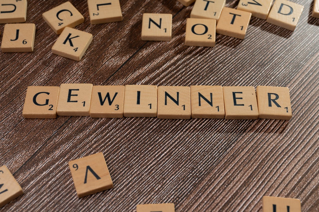 services-03 Scrabble tiles forming the word 'Gewinner' meaning winner on a wooden table.